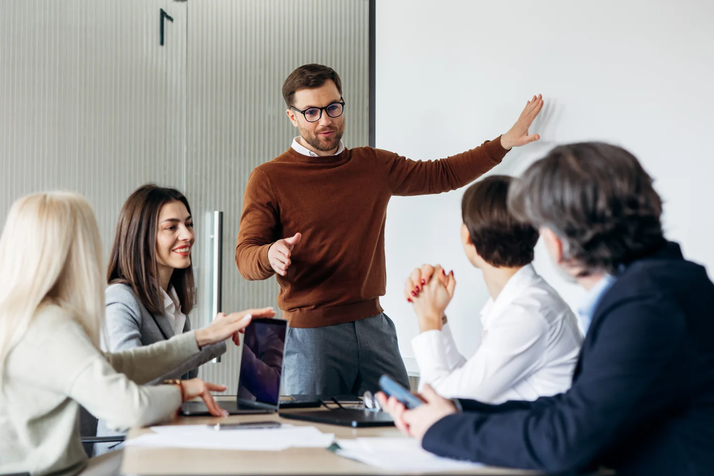 Trainer erläutert an einem Whiteboard eine Vorgehensweise, Teilnehmende diskutieren mit